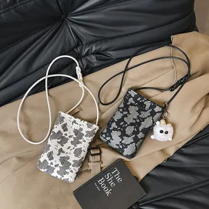 Chic cow print mini crossbody phone bag with thin shoulder strap and plush charm