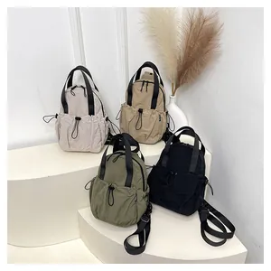 Group shot of nylon backpacks in cream, khaki, olive, and black with drawstring pockets