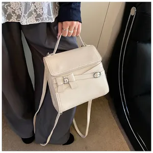 Detail van de gebroken witte crossbodytas met strikdecoratie en lederen textuur