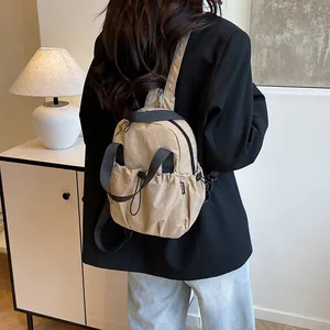 Large capacity solid nylon backpack in beige shown from a back-side view on person