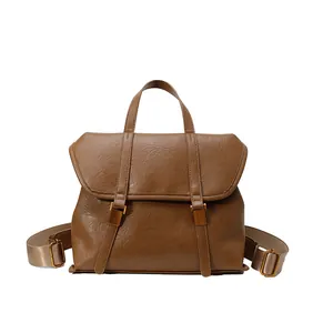 Vintage brown leather backpack and handbag with gold buckles on a clean white background