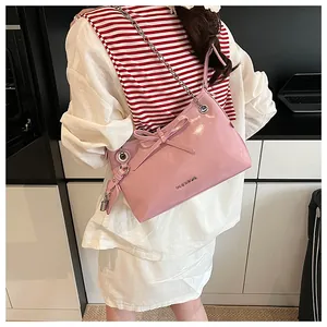 Détail d'un sac à bandoulière rose brillant avec nœud et bandoulière en chaîne argentée