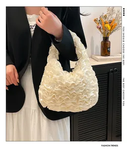 Detailed view of the creamy white ruffled handbag featuring elegant wave-like pleats texture