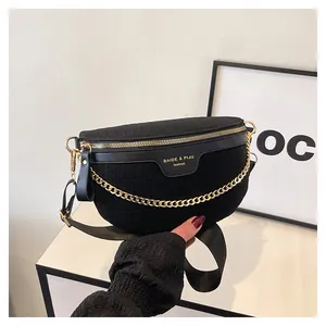 Detalle de bolso medialuna negro con cadena dorada y acabado en tejido texturizado