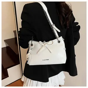 Vue détaillée du sac à nœud blanc avec bandoulière chaîne et breloque cadenas argent