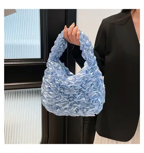 Close-up of sky blue ruffled satin handbag with elegant pleated fabric texture and handle