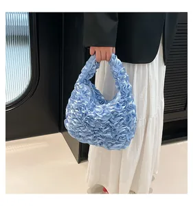 Detail of light blue pleated handbag with ruffle texture held by model in stylish outfit