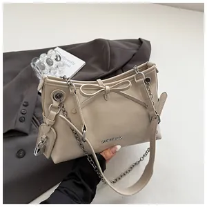 Détail d'un sac bandoulière beige en cuir avec nœud papillon et logo métallique élégant