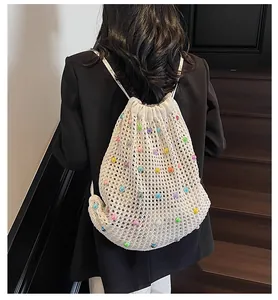 Detail of white knit drawstring backpack featuring vibrant multicolored bead embellishments