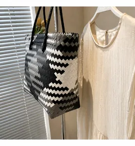 Detail showing the geometric woven pattern and sturdy black handles of the tote bag