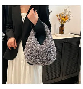 Detailed texture of the silver-grey pleated satin handbag with wavy petal pattern