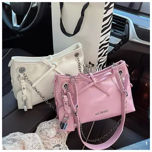 Détail des sacs à bandoulière en rose et blanc avec de grands nœuds et chaînes dorées