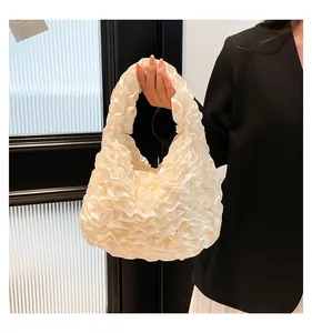 Detail of creamy white pleated handbag with satin fabric texture and ruffles