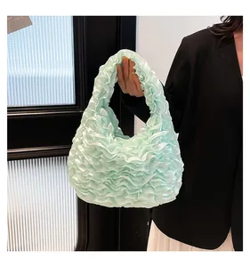 Close-up of mint green pleated ruffle handbag with soft satin fabric texture and details