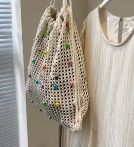 Détail du sac cabas tissé crème avec perles colorées et cordon de serrage en lumière naturelle