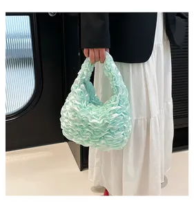 Side view of a soft mint green pleated ruffle handbag styled with a white dress