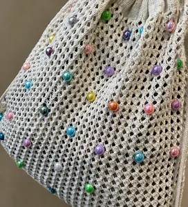 Détail d'un sac cabas tissé crème avec des perles irisées colorées et un cordon de serrage