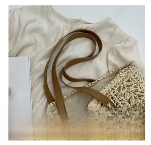 Detailed close-up of woven straw tote bag featuring reinforced brown faux leather handles