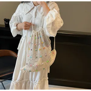 Detail of cream knit drawstring bag with colorful bead accents shown on model