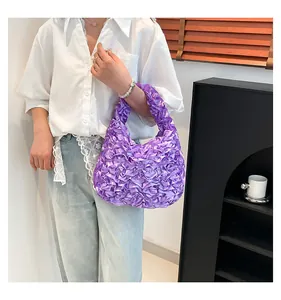 Detail of purple pleated handbag with ruffle texture and silk-like glossy finish
