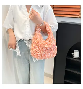 Close-up of peach pink ruffled handbag with satin texture and soft lace floral details