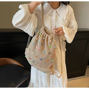 Detail of beige knit drawstring bag featuring colorful beads and textured mesh weave