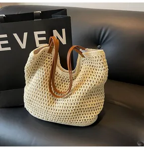Detail of hand-woven mesh tote bag with brown leather handles on a black leather sofa