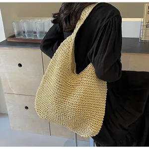 Detail of hand-woven straw tote bag showing texture and oversized shoulder strap