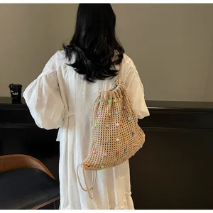Detail showing the woven knit texture and colorful beads of the beige drawstring backpack