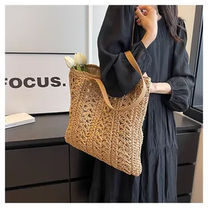 Close-up of woven tote bag showing beige hollow crochet detail and brown leather strap