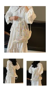 Detail of hand-woven cream knit drawstring bag with colorful beads and mesh texture