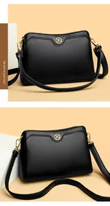 Detail of black pebbled leather crossbody bag featuring gold VG logo and adjustable strap