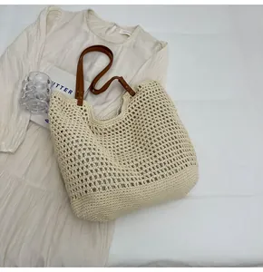 Detail of hand-woven hollow mesh tote bag with premium brown leather straps on white dress