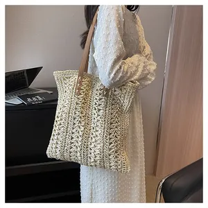 Detail of reinforced leather handle with stitching on a beige woven straw tote bag