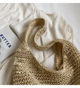 Detail of woven paper straw tote with wide shoulder straps and soft beige fabric lining