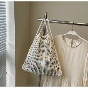 Close-up of cream woven tote bag with colorful beads and drawstring closure detail