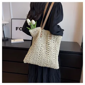 Detail of hand-woven straw tote with brown leather straps and cross-stitch accents