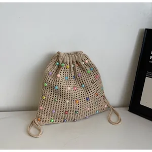 Detail of hand-woven beige knit tote bag with colorful pearls and drawstring closure