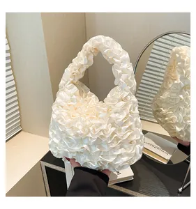 Close-up of white pleated handbag with elegant satin ruffles and soft texture details