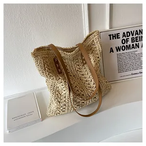 Detail of hand-woven straw tote bag with brown leather handles on minimalist display