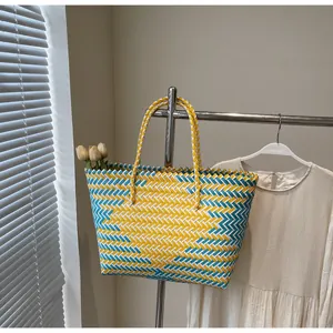 Détail d'un sac cabas tressé à motif zigzag jaune et bleu avec tulipes décoratives