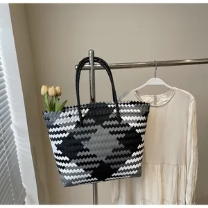 Détail du sac cabas tissé main avec motifs de losanges et des anses noires rondes