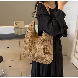 Detail of hand-woven straw hobo bag showing the dense texture and wide shoulder strap