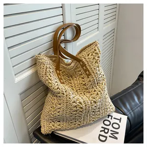 Detail of hand-woven straw tote with brown leather handles and sturdy white stitching
