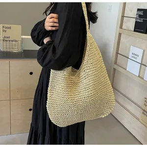 Detail of cream woven tote bag with straw texture and wide shoulder strap on model