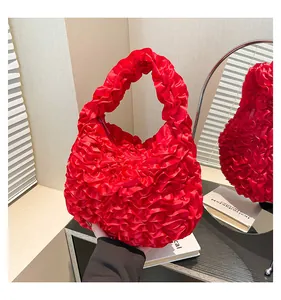 Close-up of red ruffled pleats and silky fabric texture on this casual handbag