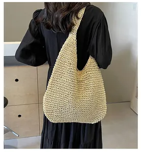 Detailed close-up of a large beige straw woven tote bag worn with a black dress