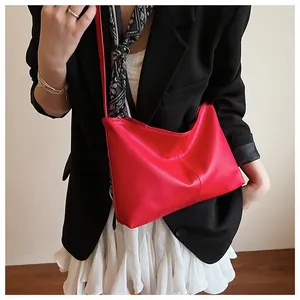 Detail of red pebbled leather crossbody bag paired with elegant black and white outfit