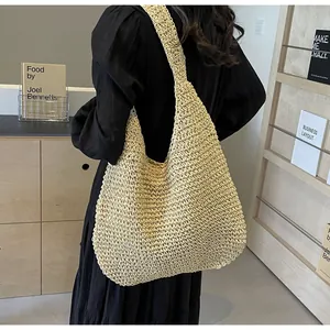 Detail of hand-woven texture on a large beige straw tote bag with wide shoulder strap