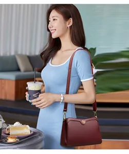 Burgundy litchi grain leather crossbody bag shown on model with gold YG metal logo detail